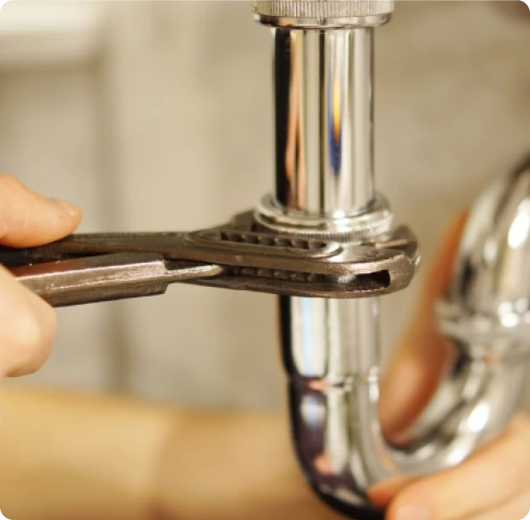 Fontanero reparando el sifón de un fregadero con una llave en Madrid